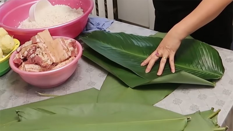 Xếp lá dong ngang sao cho lá trên chồng lên một nửa lá dưới